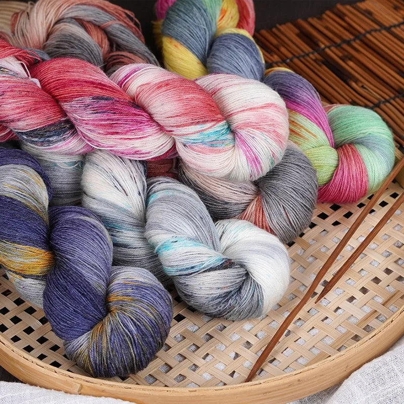 A bundle of hand-dyed Australian wool yarn in various gradient colors, including pinks, blues, greens, and purples, resting o