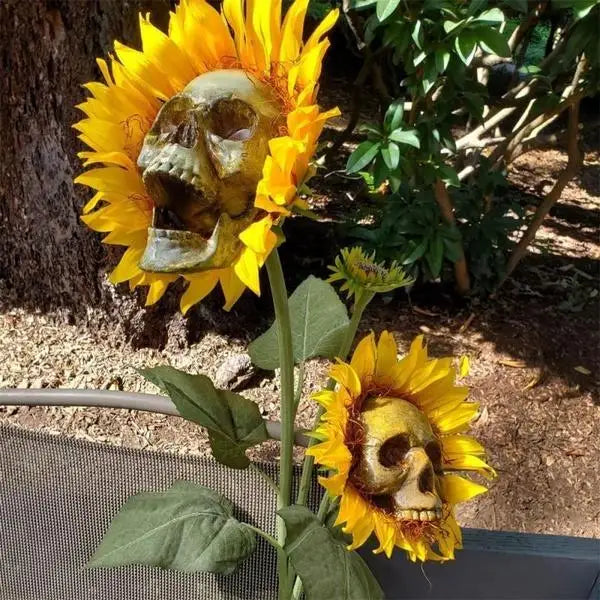 A bright yellow sunflower with a skull face decoration growing on a plant.