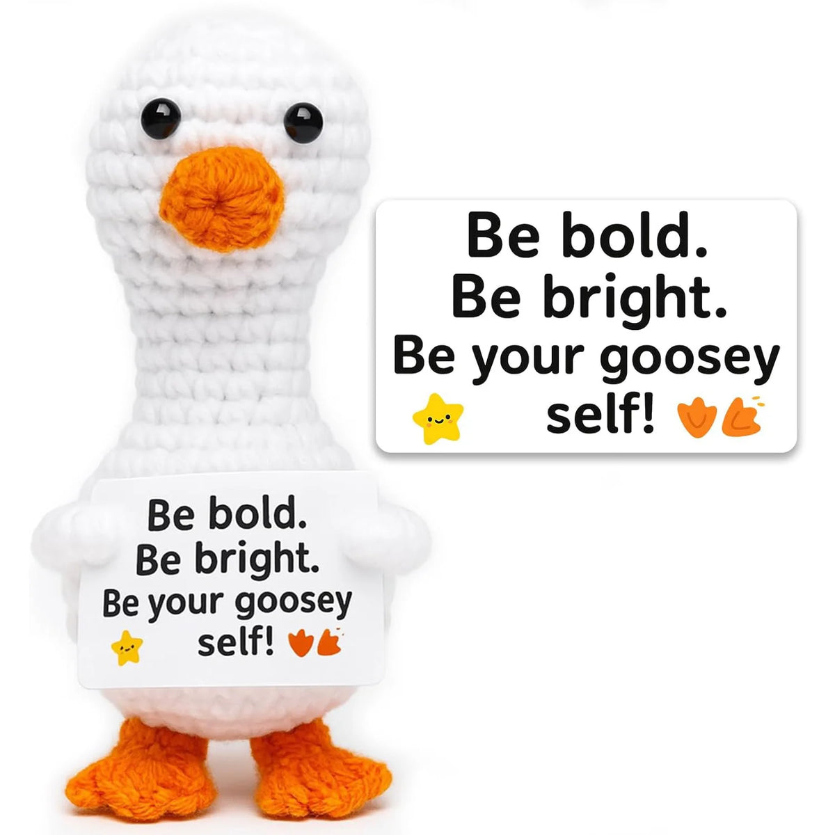 A white crochet goosey self doll with orange feet and a sign that says Be bold Be bright Be your goosey self