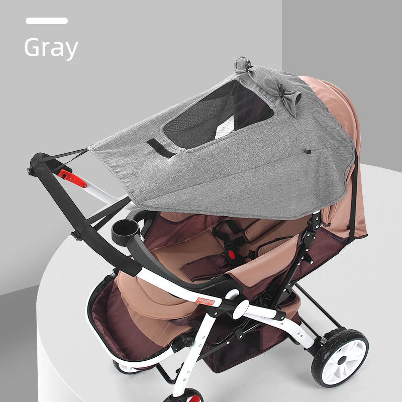 A gray universal baby stroller sun shade canopy is shown in a light pink stroller.
