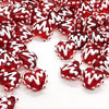 A close-up of red heart lampwork glass beads with white swirling designs scattered on a white background.