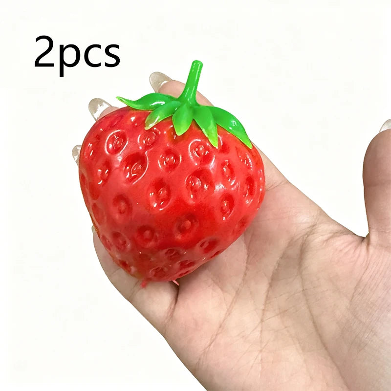 Two bright red strawberry stress balls with green tops held in a hand.