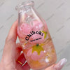 A hand holds a clear bottle filled with pink and yellow squishy fruit toys labeled Chiboki