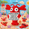 A handmade red crochet lobster doll with a motivational card and various sea creatures