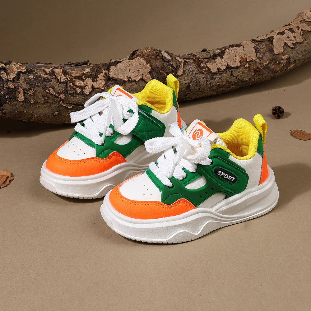 A pair of yellow and green casual sneakers with white laces and orange accents resting on a brown wooden log.