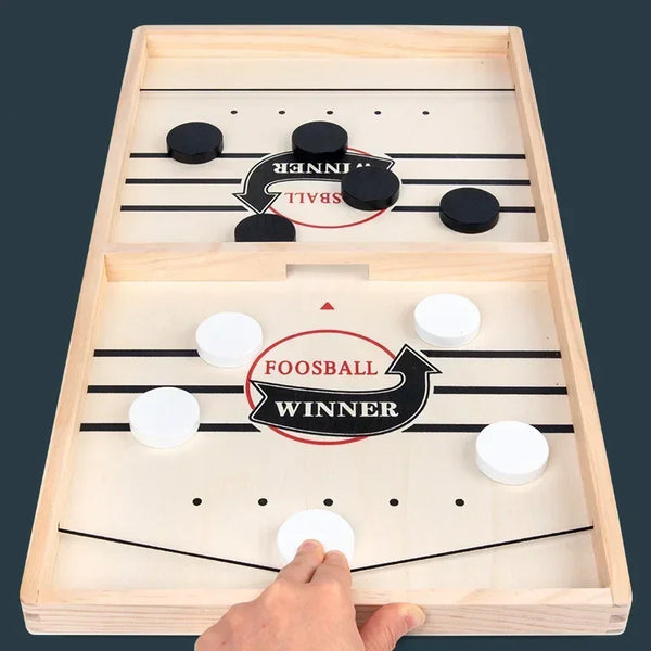 A wooden foosball game table with two playing fields, showing a winner marker on each side.