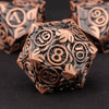 A close-up of a bronze metal dice set with intricate designs, resting on a dark surface.