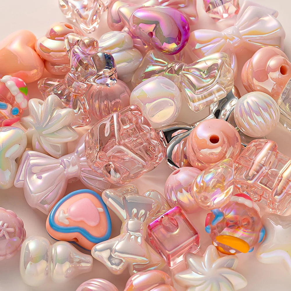 A close-up of various iridescent pink and clear acrylic bow and flower beads for DIY jewelry making