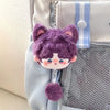 A purple fluffy cat plush pendant keychain hanging from a light blue fabric pouch.