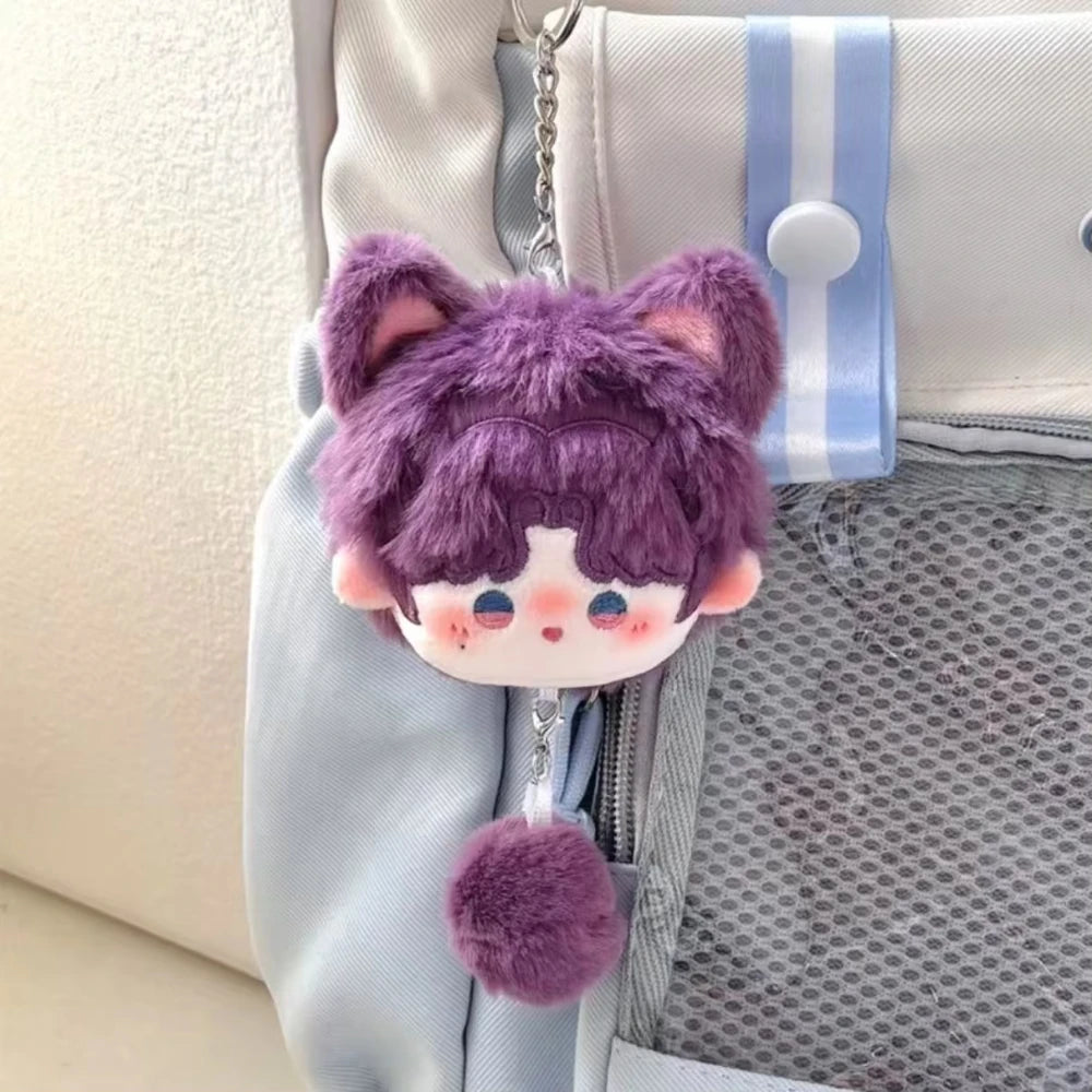 A purple fluffy cat plush pendant keychain hanging from a light blue fabric pouch.