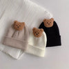 A set of three knitted baby hats featuring brown and beige colors with small bear ears.