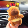 An orange capybara plush toy with yellow accents is held in a hand against a dark background.