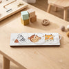 A wooden Montessori busy board featuring animal figures and sensory elements on a light wood table.