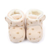 Pair of light beige baby winter snow boots with fuzzy ball accents
