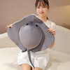 A woman holds a gray plush toy shaped like a ray devil fish, which is a soft stuffed ocean animal pillow.