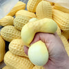 A hand is holding a large yellow squishy stress ball with a textured surface, surrounded by many similar items.