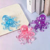 A collection of colorful fuzzy jellyfish squishy stress relief toys in blue, purple, and pink resting on a white surface.