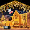 Battery-powered fairy lights draped across the roofline of a house in winter scenery.
