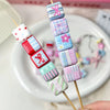 A display of colorful acrylic beads with flower and bow prints strung on wooden sticks.