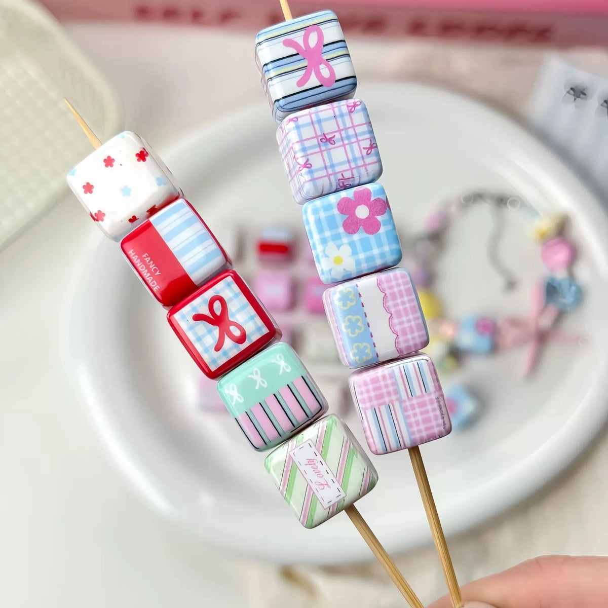 A display of colorful acrylic beads with flower and bow prints strung on wooden sticks.
