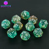 A collection of ten glittery polyhedral dice in various shades of green and translucent colors displayed on a dark surface.
