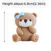 A cute, light brown bear-shaped cake topper with a blue bow and pink paws.