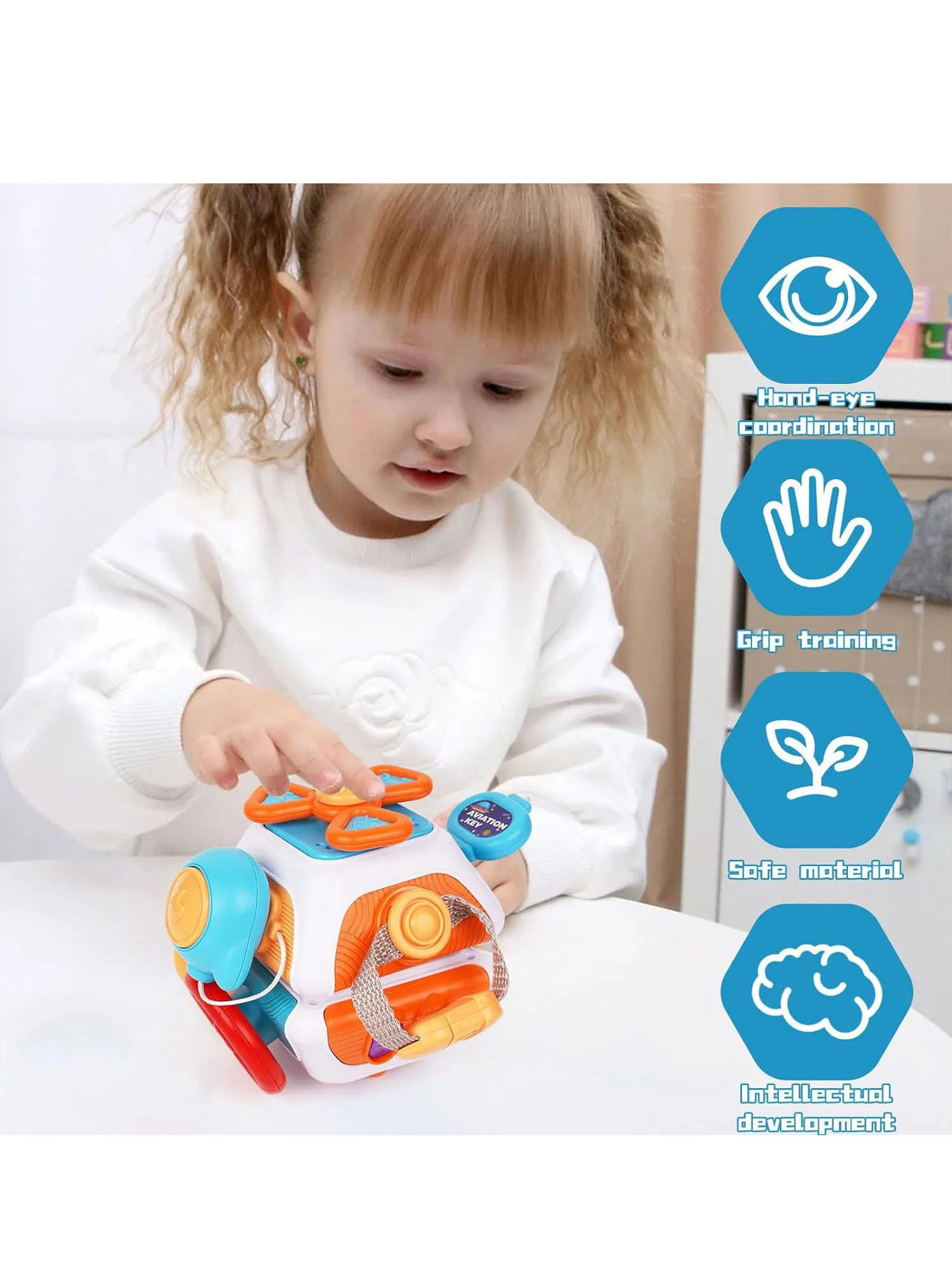 A toddler is interacting with an orange and white sensory busy board cube toy while learning hand-eye coordination and intell
