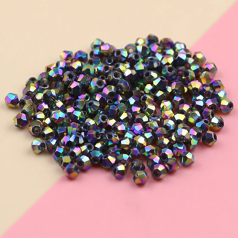 A pile of iridescent, multi-colored crystal glass beads for jewelry making spread on a pink and beige surface.