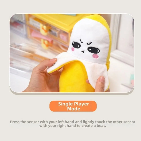 A yellow banana fruit induction metronome with a white, expressive face is shown being held by a hand.