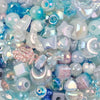 A close-up of various iridescent and translucent acrylic bow and flower beads in shades of blue, pink, and clear.