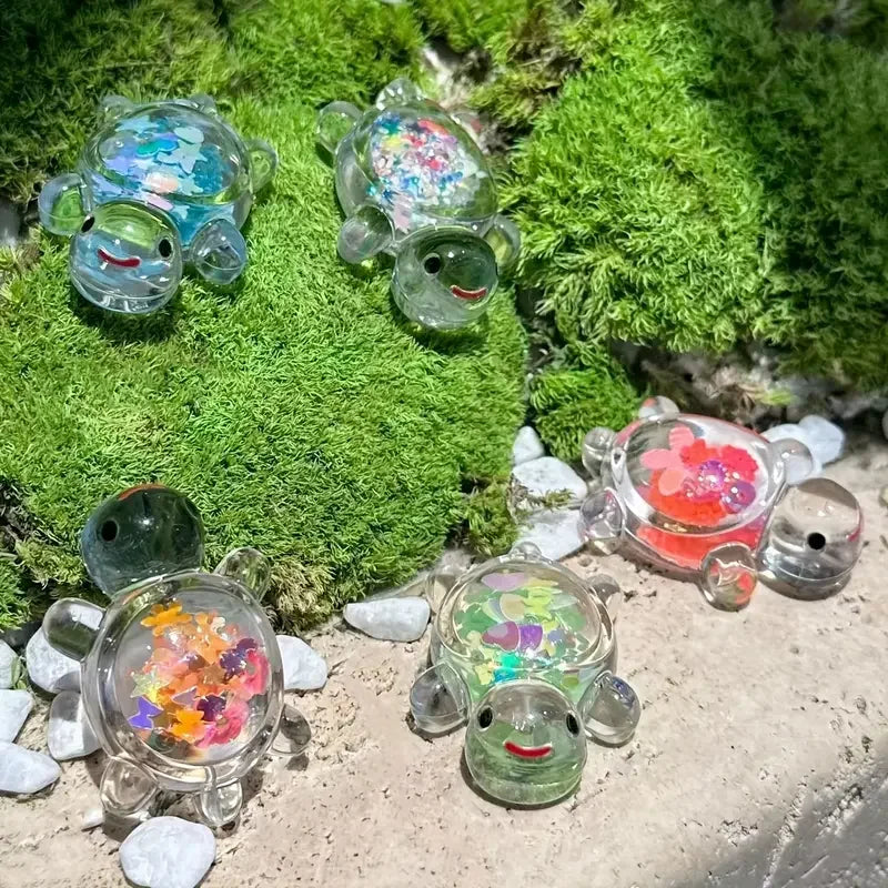 A collection of glow-in-the-dark mini sea turtle figurines in various colors resting on moss and small stones.