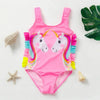 Pink kids mermaid unicorn one-piece swimsuit with rainbow trim lying on a white surface.