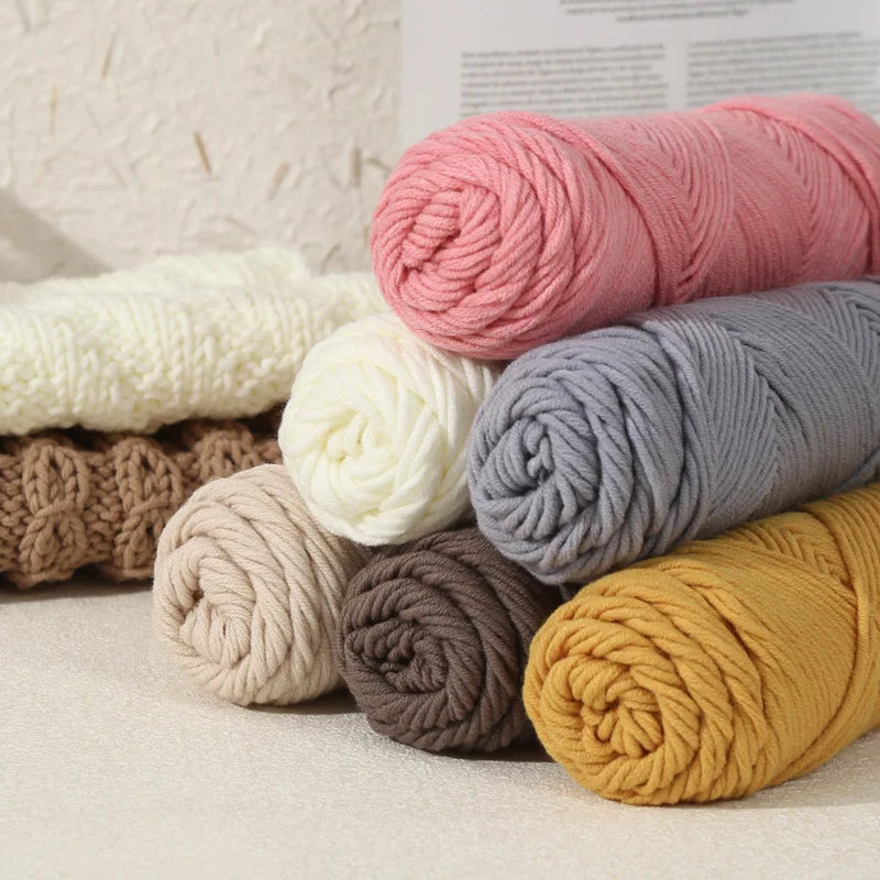 A collection of skeins of pink, white, gray, brown, and yellow premium milk cotton knitting yarn.