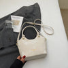 A cream canvas tote bag with gold hardware is shown next to a gray blazer and a piece of paper.