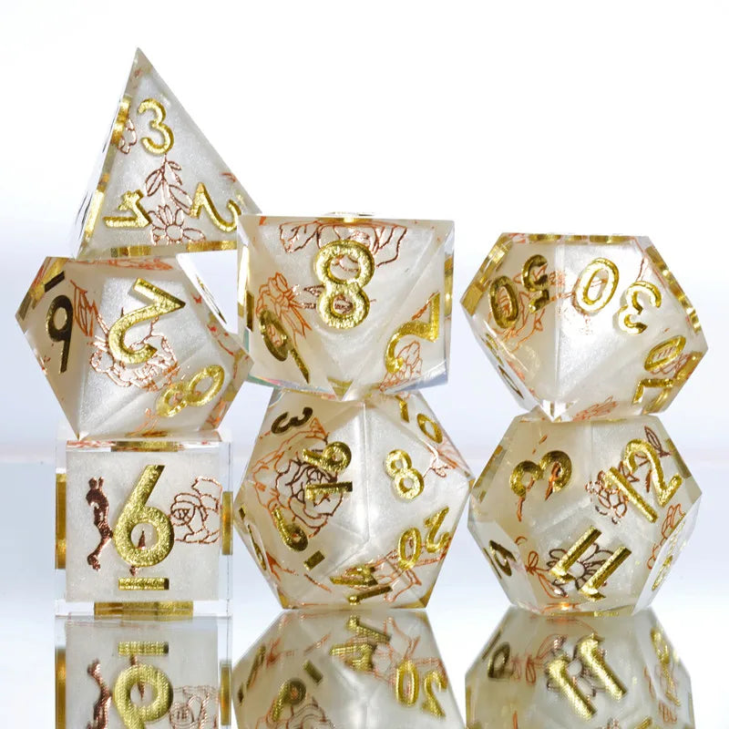 A set of handmade resin polyhedral dice in pale yellow and gold colors arranged on a reflective surface.