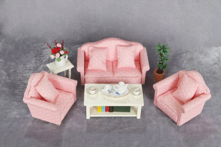 A pink 1:12 scale mini sofa and pillow set for a dollhouse displayed on a gray surface.
