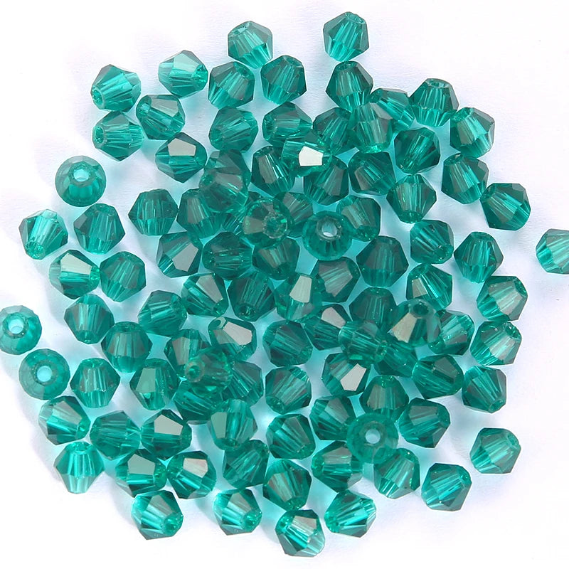 A cluster of small, faceted, teal green bicone glass beads for jewelry making.
