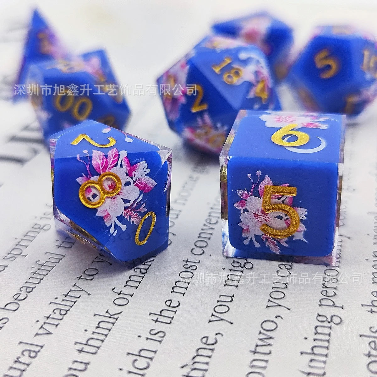 A set of blue resin dice showing numbers 0 through 6 with black kitten designs on a white background.