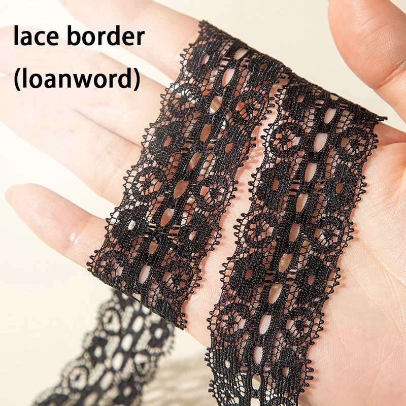 Close-up of black lace border shoelaces being held by a hand