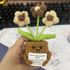 Handmade crochet sunflower plant with a brown pot and green leaves resting on paper.