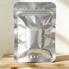 A sealed silver foil pouch of DIY clay for handcrafted jewelry making resting on a wooden surface.