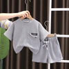 A gray boys' summer cotton t-shirt and shorts set displayed on a hanger against a dark background.