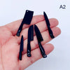 A set of miniature black metal kitchen knives held in a person's hand.