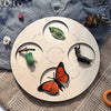 A wooden circular display featuring various natural elements like a leaf, a stick, and an orange butterfly.