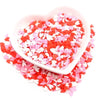 A heart-shaped dish filled with red and pink polymer clay sprinkles for slime and craft decor