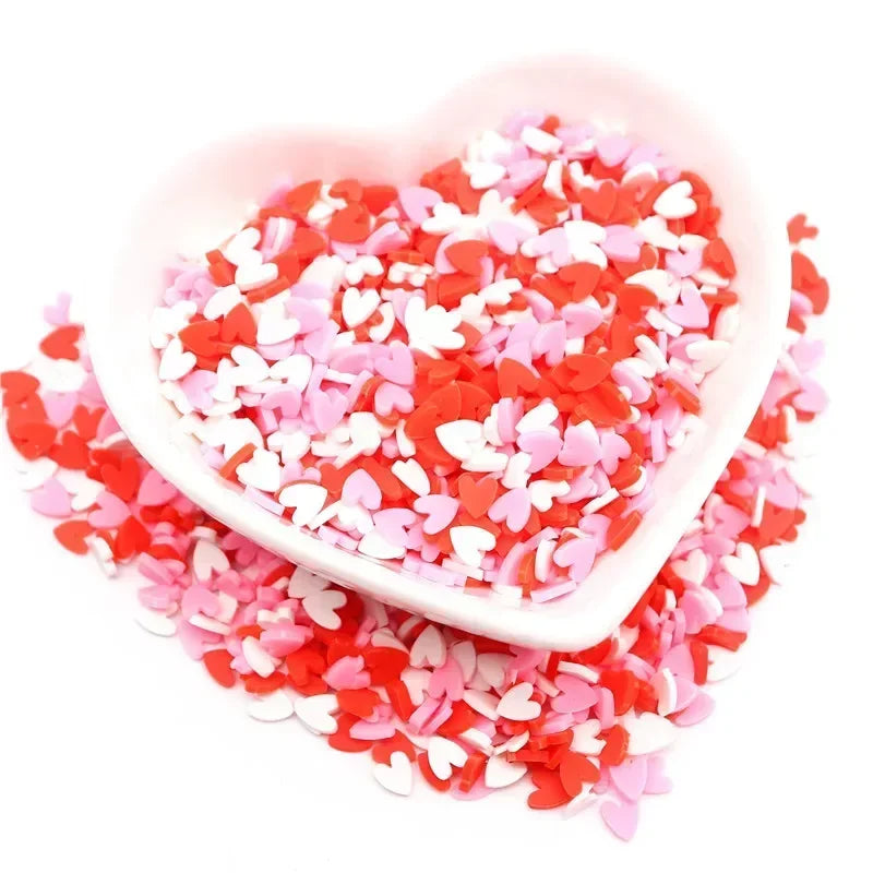 A heart-shaped dish filled with red and pink polymer clay sprinkles for slime and craft decor