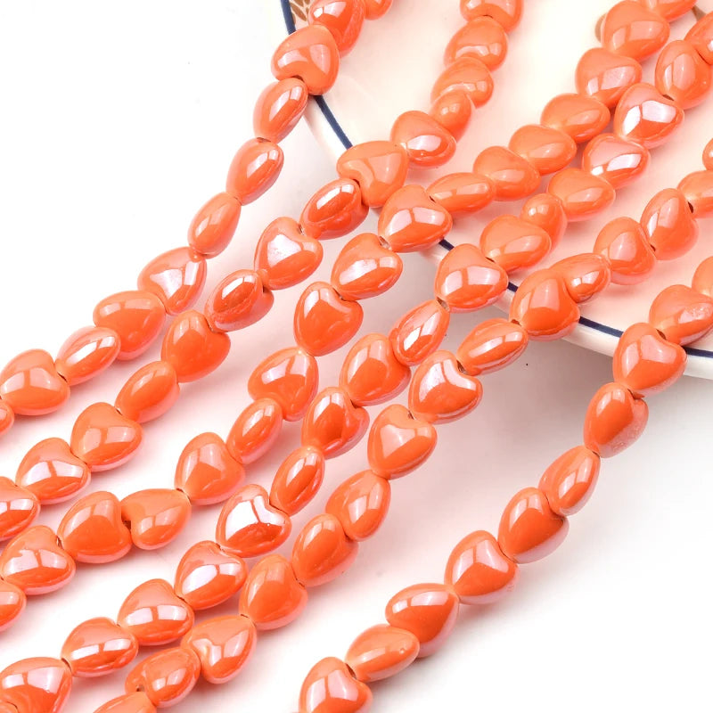 A string of small, orange heart-shaped acrylic beads for jewelry making.