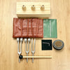 A set of sound healing tuning forks and a wooden resonance box are displayed on a light wood surface.