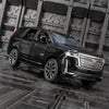 A black 1:32 diecast Cadillac Escalade pull-back model car parked on a dark metal surface.