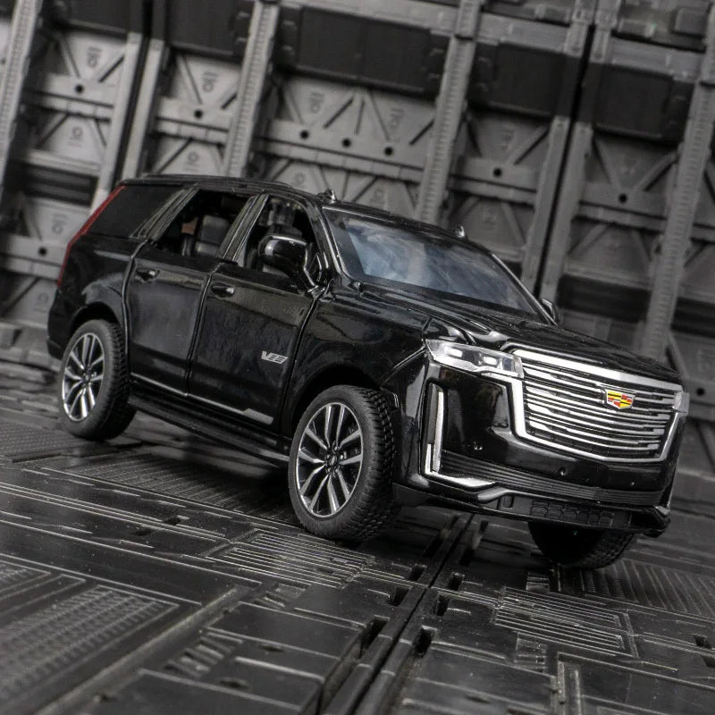 A black 1:32 diecast Cadillac Escalade pull-back model car parked on a dark metal surface.